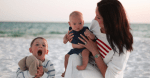 woman on beach wearing american flag sweater with two small children