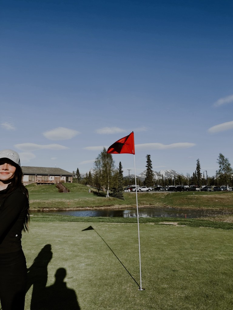 girl on golf course at anchorage golf course with mountain views behind