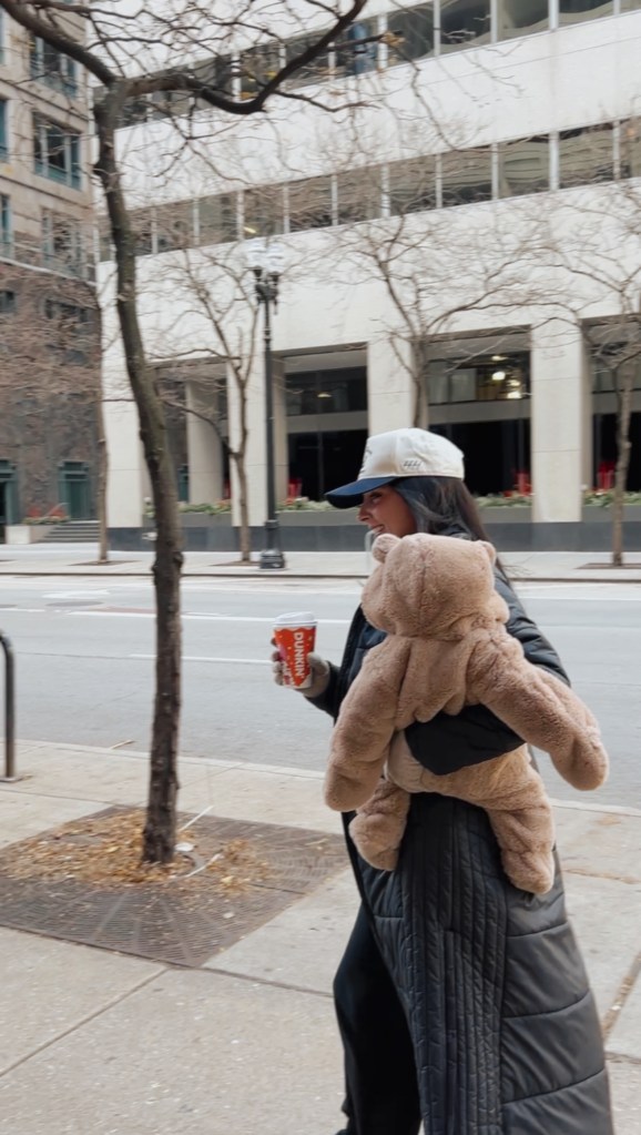 woman walking in chicago in winter carrying baby and a dunkin donuts coffee cup